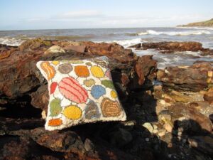 Handmade Woollen pebble cushion on a Cumbrian beach