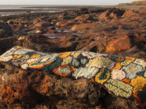 Hand made Woollen textiles on west Cumbrian beach. Embracing the environment and its colours